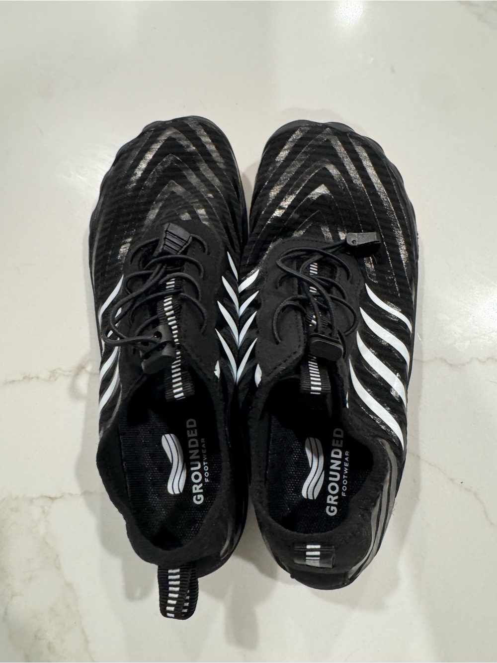 Grounded Black Athletic Shoes with White Stripes